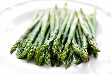 Fresh tasty asparagus in a plate on a white background