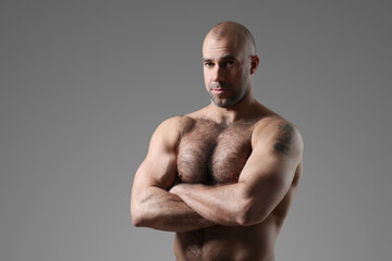 Portrait of a sporty, confident, muscular bodybuilder with a naked torso posing with crossed hands 
