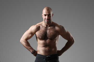 Fototapeta premium Portrait of a sporty, confident, muscular bodybuilder with a naked torso posing with hands on hips