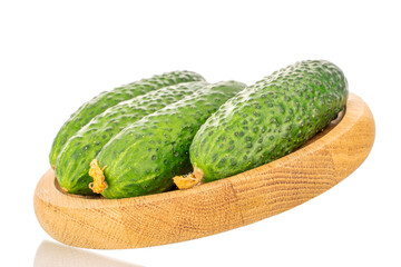 Several organic green cucumbers on a wooden tray, close-up, isolated on a white background.