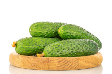 Several organic green cucumbers on a wooden tray, close-up, isolated on a white background.