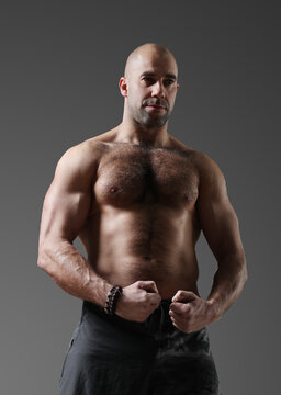 A photo of a sporty muscular bodybuilder with a naked torso posing on camera