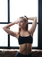 Beautiful young blonde woman in sportswear posing in gym 