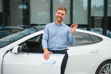 Always available. Handsome young businessman near his car outdoors