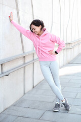 Young beautiful girl in pink sportswear with hood posing outdoor