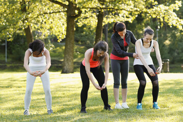 Full length of people doing stretching exercise in the park