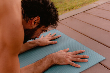 Young beautiful man practicing ashtanga yoga at sunset on the beach. Doing exercises and...