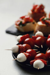 Delicious fresh bruschetta with cherry tomatoes on a black wooden cutting board