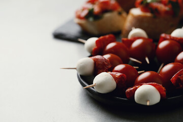 Delicious fresh bruschetta with cherry tomatoes and mozarella cheese on a black wooden cutting board