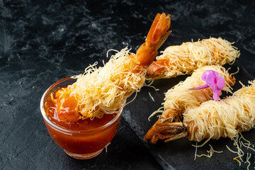 Appetizing appetizer of crispy prawns in kataifi dough and sweet and sour sauce.