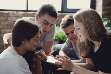 A group of teenagers spending time together and looking at the phone at home
