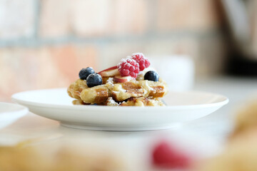 Side view of breakfast of tasty mini Waffles with berries on a white plate