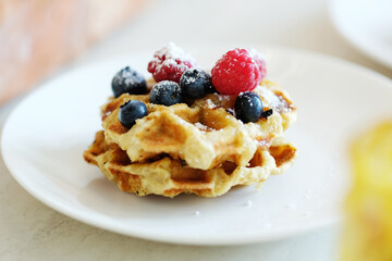 Breakfast of tasty mini Waffles with berries on a white plate
