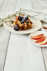 Belgian waffles with berries and powdered sugar on a wooden surface.