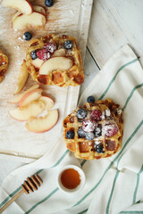 Belgian waffles with berries and powdered sugar on a wooden surface.