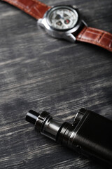  E cigarette with stylish watch on a dark wooden background