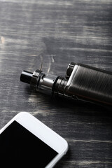  E cigarette with an Iphone on a dark wooden background