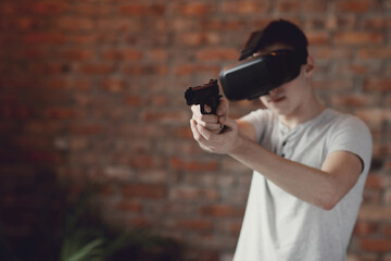 Teen playing with virtual reality glasses with toy gun in hands