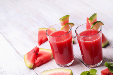 Watermelon smothie and slices with lime on a wooden surface