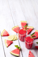 Watermelon smothie and slices with lime on a wooden surface