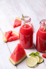 Watermelon smothie and slices with lime on a wooden surface