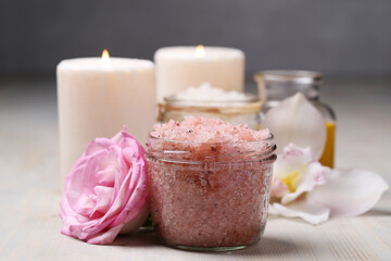 A glass jar of pink sea salt and two candles for cosmetologic procedures