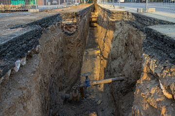 Repair work to replace the city water main. Uncovered asphalt and a deep trench