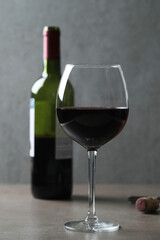 One glass of red wine with corkscrew  and bottle on a dark surface