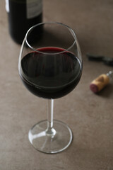 One glass of red wine with corkscrew on a dark surface