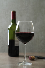 One glass of red wine with corkscrew  and bottle on a dark surface