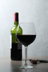 One glass of red wine with corkscrew  and bottle on a dark surface
