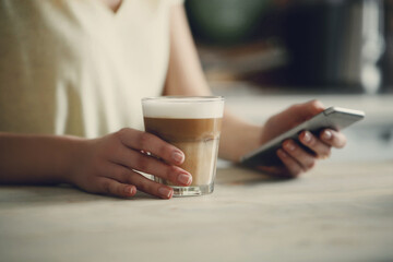 Woman`s hand holding a morning cup of aroma coffee at the kitchen
