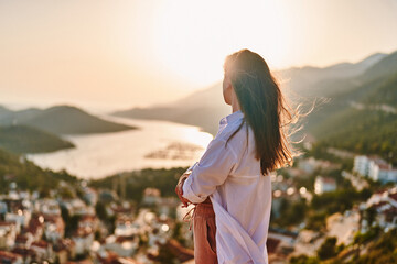 Calm serene thoughtful female stands alone and looks into the distance at beautiful view at sunset