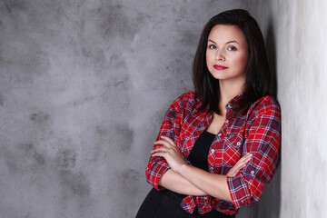 Photo of gorgeous , adorable , brunette woman in a plaid shirt posing with crossed arms isolated on dark color background