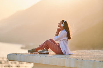 Inspired happy serene female with closed eyes enjoying of listening calm music with beautiful view...