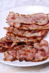 Hot fried bacon slices in a white plate