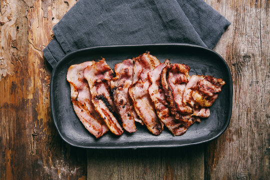 Hot fried bacon slices in a cast iron plate
