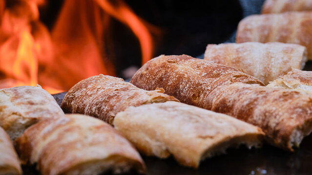 Close up detail view of sandwiches grilled on flat surface barbecue in front of red open fire