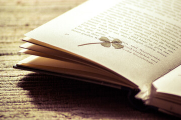 Ein gepresstes vierblättriges Kleeblatt liegt auf Seite 42 eines geöffneten Buches