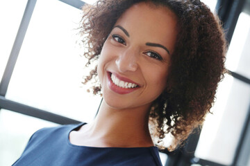 Close-up image of a smilng,beautiful woman with curly hair looking into the camera