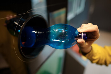 Woman puts bottle in automatic bottle recycling machine. Reverse vending recycling machine.