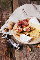 Delicious food with cheese , figs and nuts on a wooden surface.