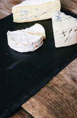 Fresh camembert cheese with sliced camembert isolated on a dark cutting board.
