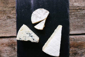 Fresh camembert cheese with sliced camembert isolated on a dark cutting board.