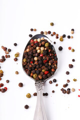 Spoon with mixed peppercorns on white background