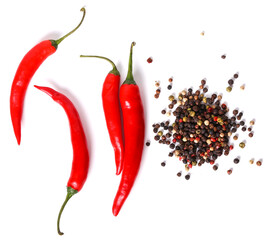 Black, red, white, and green peppercorns with four red hot chili peppers on a white background. 