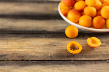 Ripe juicy apricot in a plate on a wooden table.