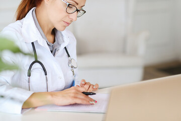 Woman-doctor sitting and working with medication history record forms in hospital or clinic