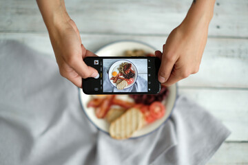 Top view of man`s hands taking picture of English breakfast with fried eggs, bacon,bread and...