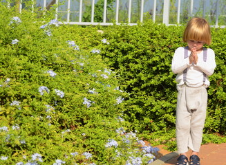 Positive child on vacation. The boy is walking in the park. Boy with suspenders and long hair....